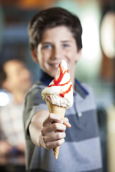 Ragazzo sorridente che mostra delizioso gelato con sciroppo di fragole — Foto Stock