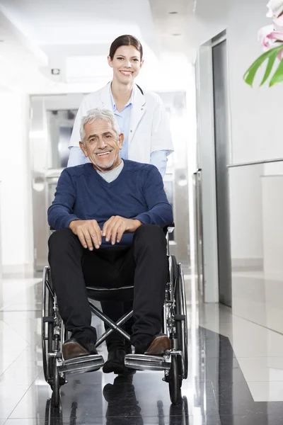 Medico femminile che spinge il paziente anziano sulla sedia a rotelle — Foto Stock