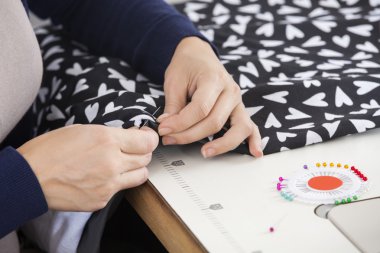 Female Tailor Stitching Fabric At Workbench clipart