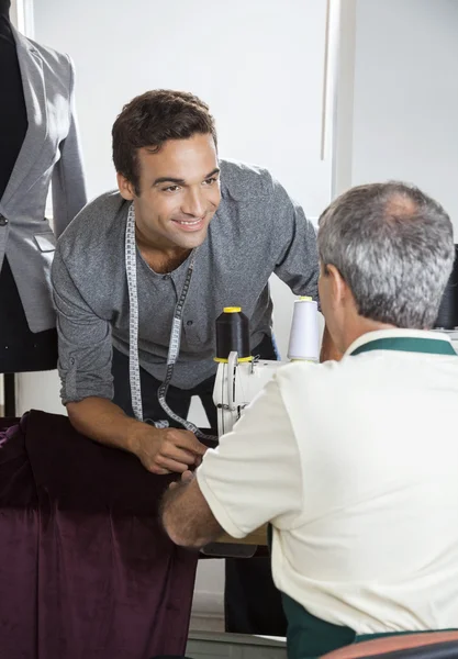 Modedesigner diskuterar med kollega på arbetsbänken — Stockfoto