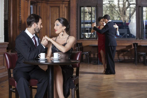 Casal segurando as mãos enquanto homem e mulher realizando tango — Fotografia de Stock