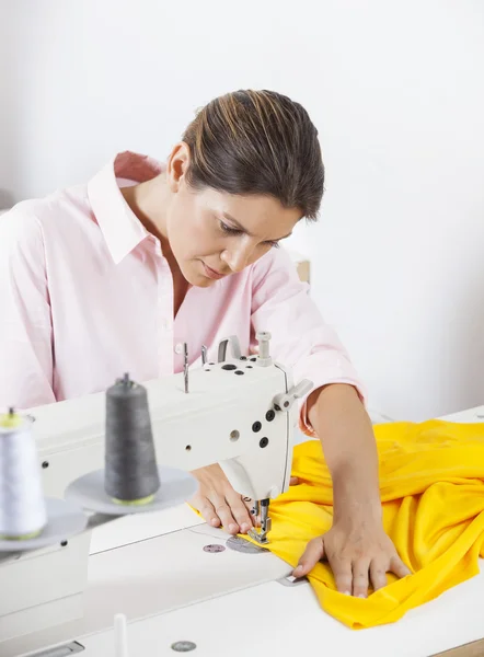 Alfaiate costurar tecido amarelo na bancada — Fotografia de Stock