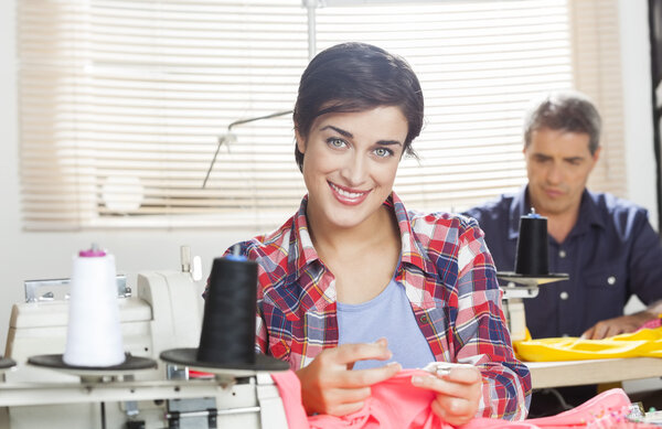 Confident Tailor Sitting At Workbench In Sewing Factory