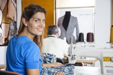 Gülümseyerek terzi dikiş makinesi kullanarak portresi