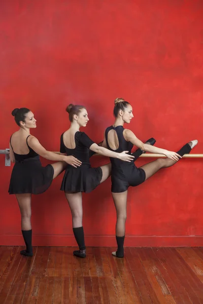 Ballerina's beoefenen op Barre tegen rode muur — Stockfoto
