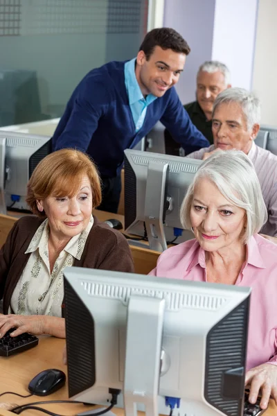 Compagni di classe anziani che utilizzano il computer in classe — Foto Stock