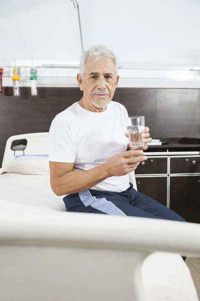 Старший человек держит стакан воды в реабилитационном центре — стоковое фото
