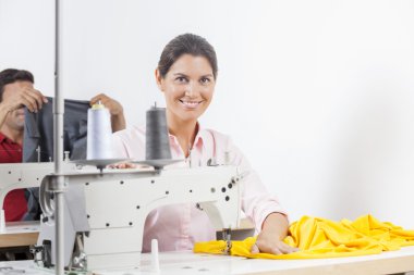 Tezgah oturan gülümseyen kadın terzi