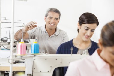 Mutlu terzi dikiş fabrikasında çalışmaya meslektaşları ile oturan