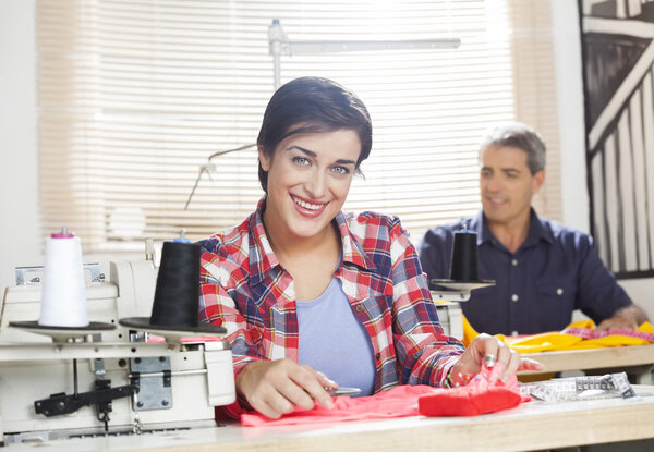 Happy Worker Sitting At Workbench In Sewing Factory