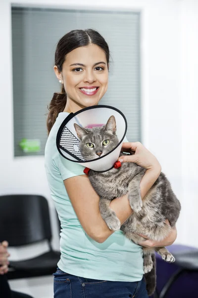 Mulher adulta média transportando gato com cone na clínica — Fotografia de Stock