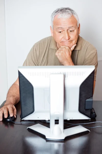 Задумчивый пожилой человек с помощью компьютера в классе — стоковое фото