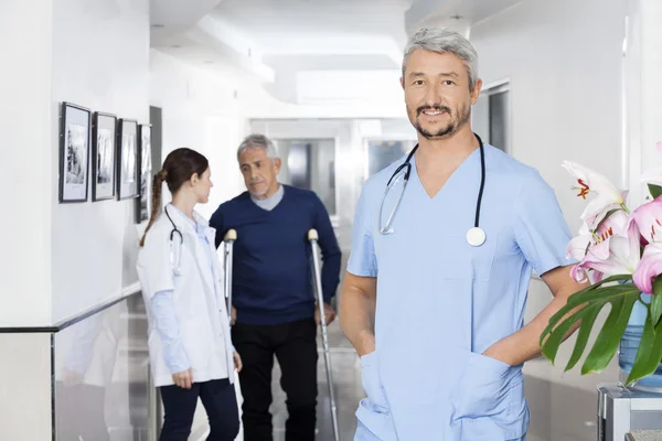 Confident Doctor Standing With Colleague And Patient In Backgrou — Stock Photo, Image