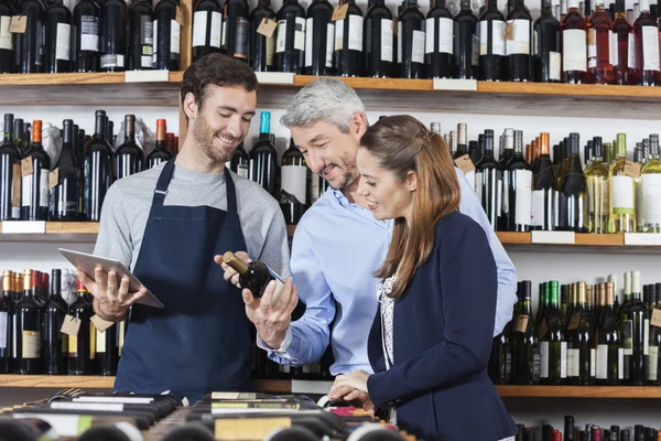 Echtpaar met verkoper lezing etiket op de wijnfles — Stockfoto