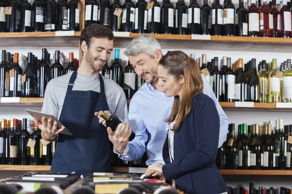 Paar mit Verkäufer liest Etikett auf Weinflasche — Stockfoto