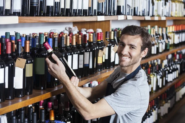 ワイン · ボトルの棚の上を整理のセールスマンを笑顔 — ストック写真