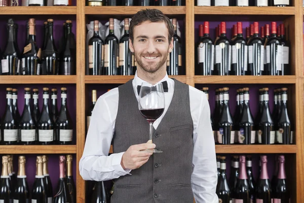 Barman rode wijnglas houden tegen planken — Stockfoto