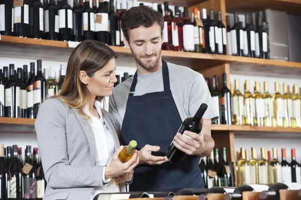 Vendeur montrant la bouteille de vin à la cliente — Photo