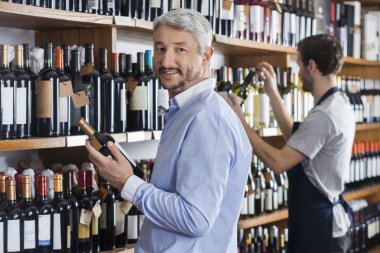 Şarap şişesi tutarak müşteri satıcı dükkanda çalışan iken