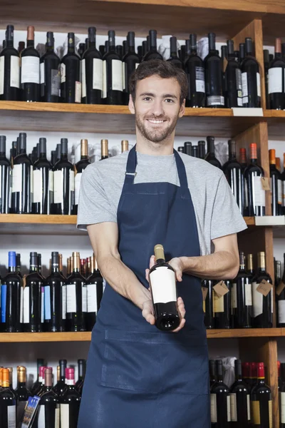 Vendedor confiante mostrando garrafa de vinho — Fotografia de Stock