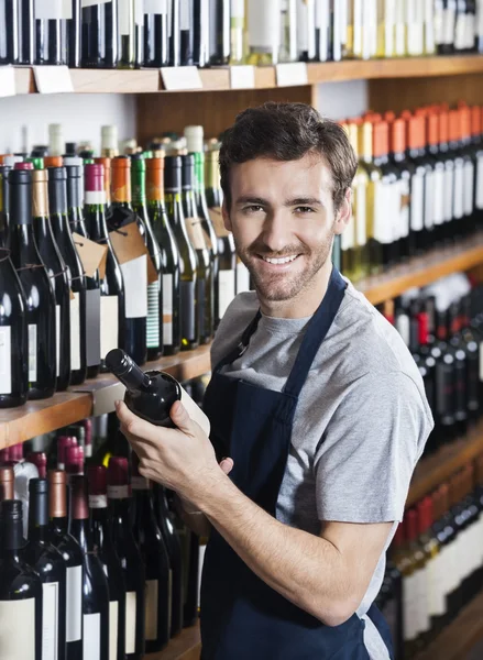 Vendedor confiante que arranja a garrafa de vinho na prateleira — Fotografia de Stock