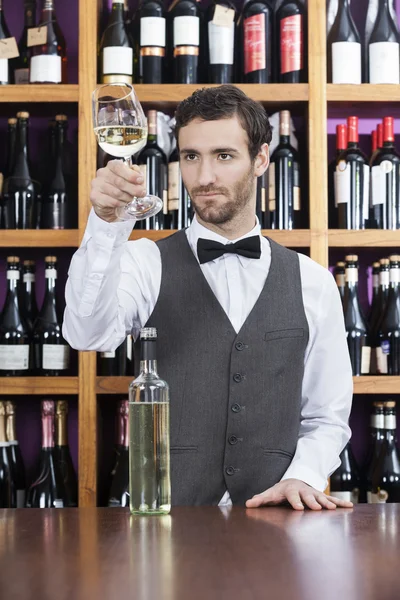 Barista esaminando vino bianco in vetro al negozio — Foto Stock