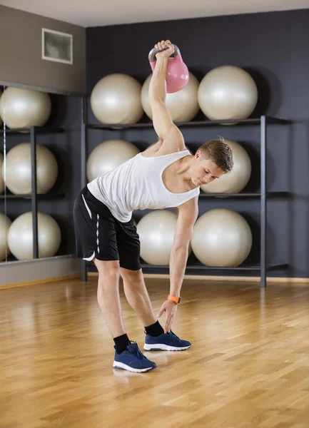 Homem se exercitando ao levantar Kettlebell no chão no ginásio — Fotografia de Stock