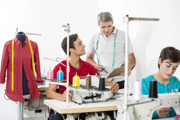 Tailors discutiendo sobre el portapapeles en fábrica — Foto de Stock