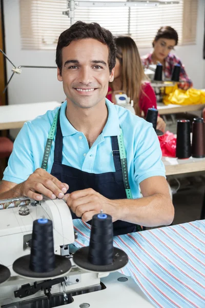 Sastre feliz sentado en el banco de trabajo en la fábrica de costura —  Fotos de Stock