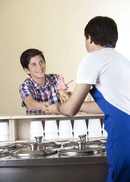 Chłopiec, płacąc za lody truskawkowe do kelnera w salonie — Zdjęcie stockowe