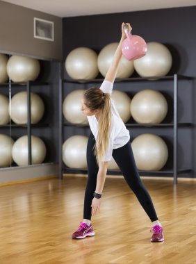 G, ahşap döşeme üzerinde kettlebell kaldırma sırasında egzersiz kadın