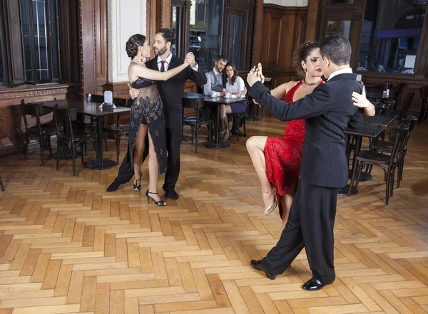 Dançarinos realizando tango no chão de madeira dura enquanto casal Namoro — Fotografia de Stock