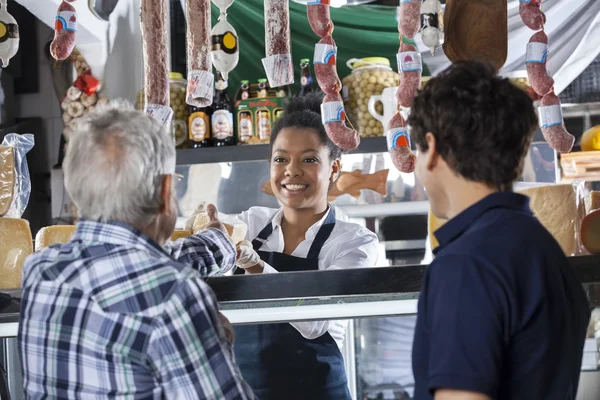 Vendedora vendendo queijo aos clientes na loja — Fotografia de Stock