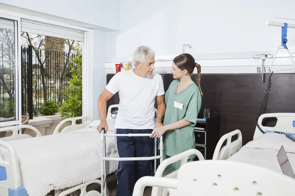 Krankenschwester hilft männlichem Patienten bei Rollator-Einsatz im Pflegeheim — Stockfoto
