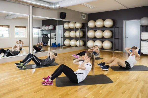 Amigos haciendo Situps en piso de madera dura en el gimnasio — Foto de Stock