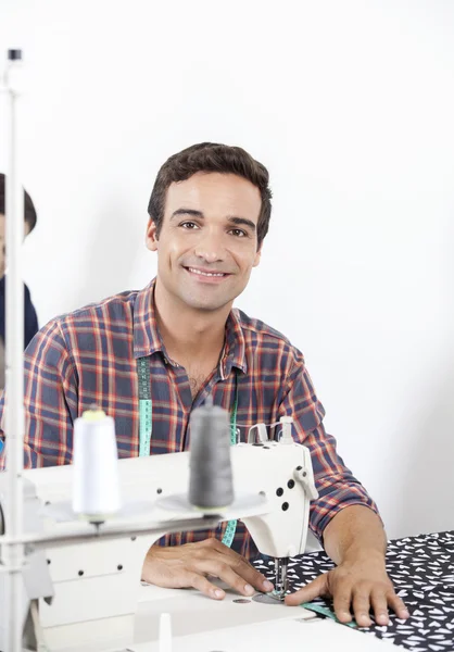 Sastre sonriente sentado en el banco de trabajo en fábrica — Foto de Stock