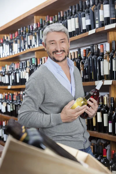 Feliz maduro cliente segurando garrafas de vinho — Fotografia de Stock