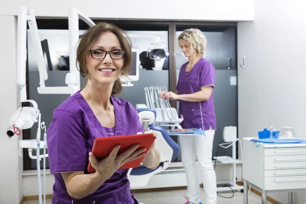 Assistente Sorrindo Segurando Tablet Digital Enquanto Colega Trabalhando — Fotografia de Stock