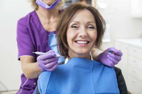 Paciente femenina sonriente con herramientas de sujeción para dentistas —  Fotos de Stock