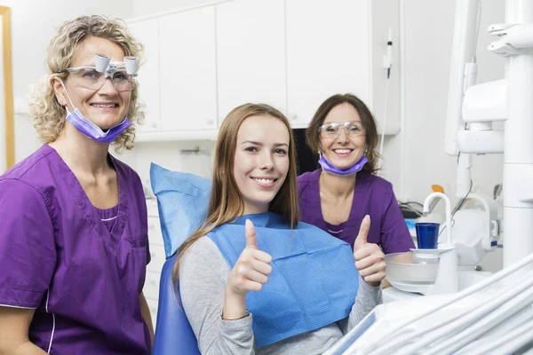 Dentistas sorrindo enquanto paciente Gesturing polegares para cima na clínica — Fotografia de Stock