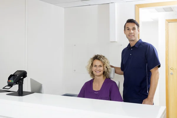 Säker tandläkare leende i receptionen på klinik — Stockfoto