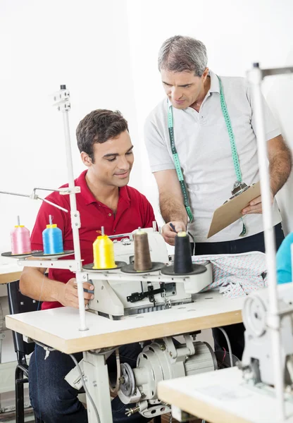 Schneiderinnen diskutieren über Klemmbrett in Nähfabrik — Stockfoto