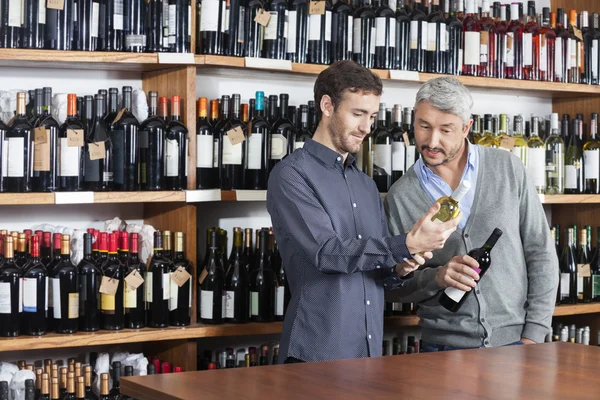 Masculino amigos leitura etiqueta de garrafas de vinho na loja — Fotografia de Stock