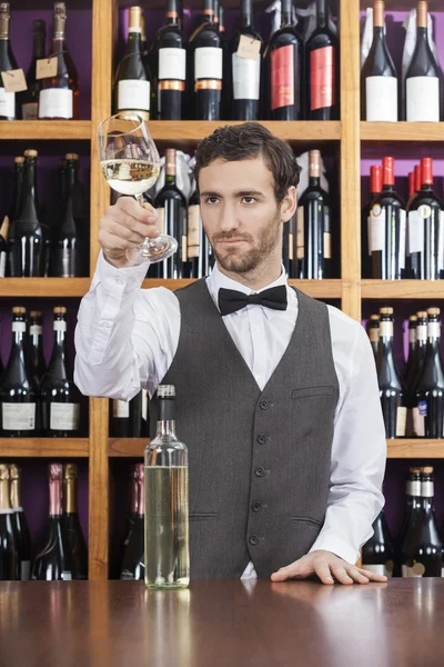 Barman, badając białe wino w szkle w kasie sklepu — Zdjęcie stockowe