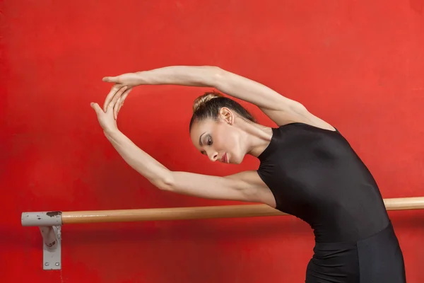 Baletka, táhnoucí se zbraněmi v tanečním studiu — Stock fotografie