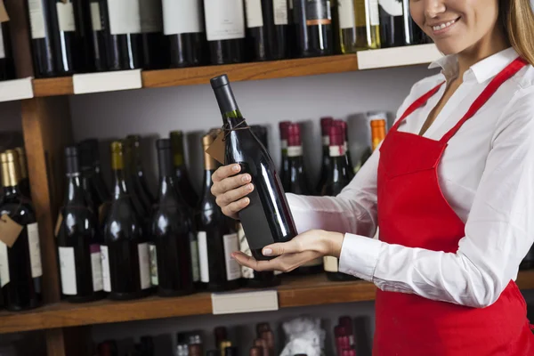 Souriante vendeuse tenant une bouteille de vin au supermarché — Photo