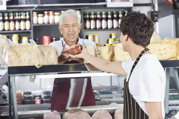 Szczęśliwy sprzedawca odbiera ser z kolega w sklep spożywczy — Zdjęcie stockowe