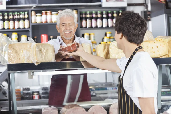 Happy Salesman Receiving Cheese From Colleague In Grocery Shop — Stock Photo, Image