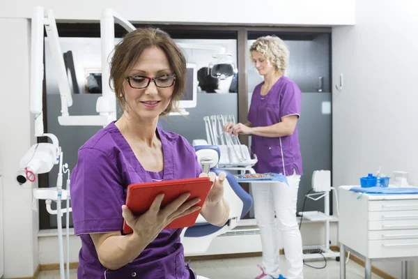 Assistente Usando Tablet Digital Enquanto Colega Trabalhando em Dentis — Fotografia de Stock