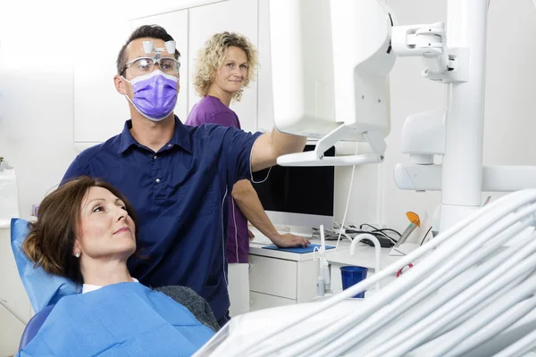 Dentista Masculino Examinando Paciente Enquanto Assistente Trabalhando na Clínica — Fotografia de Stock